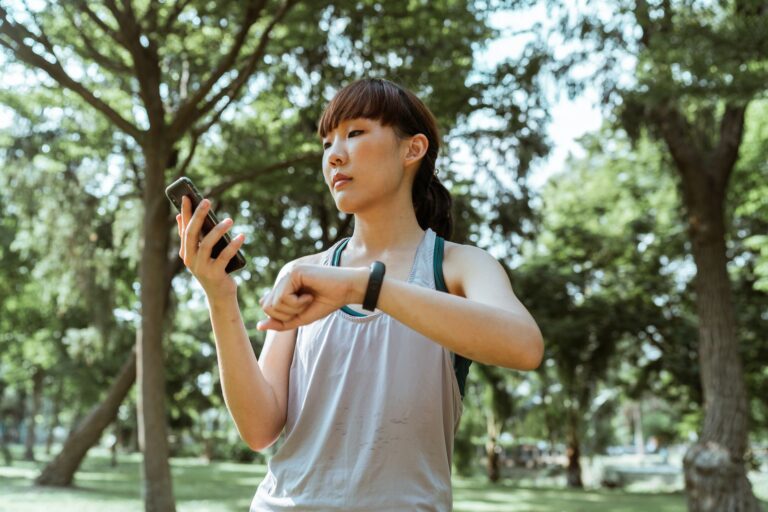 Combien de pas par jour — personne marchant dans un parc avec un podomètre